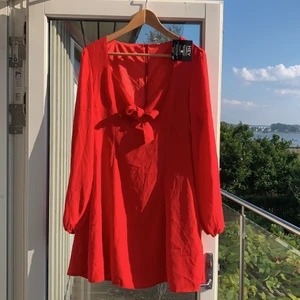 Röd klänning Oanvänd  - Helt ny röd klänning från Nelly. Söt knytning vid bysten. Prislappen kvar. Relativt liten i storlek, passar kanske 38. Köparen står för frakten. 