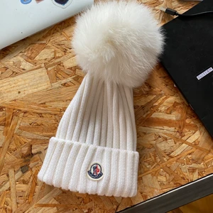 Vit Moncler Pom pom Mössa / Beanie  - Moncler vit Pompom mössa. Med sju-gradig stickning och rävpäls-pompom.  Använd max 3-4 gånger, så gott som nyskick. Köpt från ssense.com i julas för 3000kr. Mössan har märkning och QR-kod på insidan som tar en till monclers egna hemsida. Bara att skriva ifall fler bilder önskas!