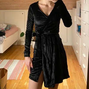 Svart klänning - Aldrig använd-lapparna kvar. Velvet wrap dress från Nelly. Knytning i midjan. Storlek xs, jag är 165 cm lång. 