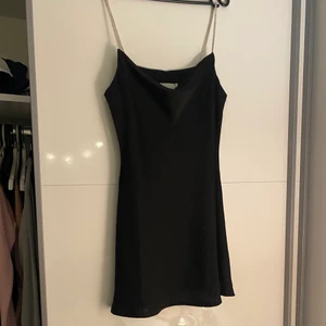 Trendig svart klänning med glitter   - Säljer min svarta klänning som känns som silke. Storleken är S. Banden har fina glitterdetalj och klänningen går inåt vid midjan vilket ger en fin form när man har på sig den. Köpt i Spanien för en månad sedan men inte använd. Skriv för fler bilder. 