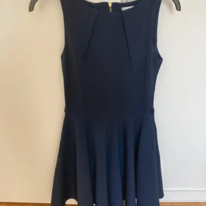 Bal/avslutnings klänning - Snygg mörkblå klänning med ärmlös design och rund halsringning. Klänningen har en figurnära överdel och utställd kjol, perfekt för en stilren look. Dragkedja i ryggen för enkel på- och avtagning. Enbart testad. Utmärkt skick! 