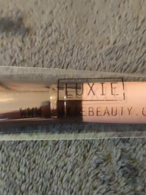 Luxie rosa vinklad sminkborste - Säljer en snygg vinklad sminkborste från Luxie med ljusrosa handtag och metalliskt roséguld vid borstfästet. Borsten har täta, mjuka strån och passar perfekt för contour eller rouge. Handtaget är i plast och borsten är vegansk.