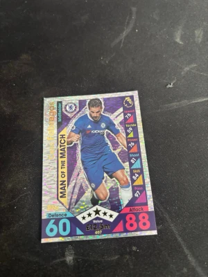 Fabregas Match Attax Chelsea Man of the Match kort - Säljer ett Match Attax samlarkort från Topps med Chelsea FC-tema. Kortet är holografiskt och visar en mittfältare med texten 'Man of the Match'. Flera stats som Speed, Tackle och Power finns på framsidan. Perfekt för dig som samlar på fotbollskort eller gillar Premier League.