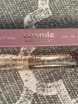 Cosmic parfym från Kylie Jenner 10 ml - Cosmic parfym från Kylie Jenner i en smal, genomskinlig glasflaska med rosa text. Flaskan rymmer 10 ml och kommer i en snygg lila kartong med metallicdetaljer. Perfekt att ha med i väskan för en fräsch doft när som helst. Ny!