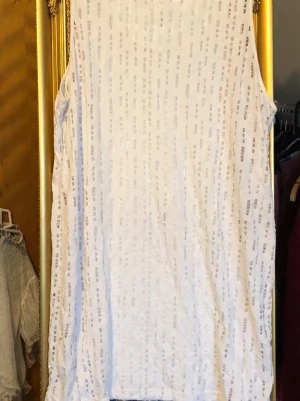 Vit glittrig linnetopp från Monki - Snyggt vitt linne i stretch från Monki med glittriga detaljer i ett diskret mönster. Storlek: L. Längd: 80cm och 56cm armhåla till armhåla. 55kr