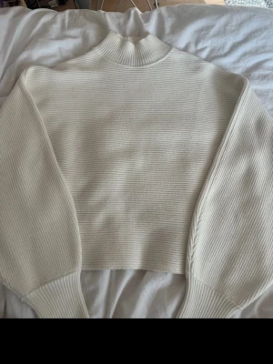 Vit ribbstickad tröja med krage - Säljer en stilren vit ribbstickad tröja med hög krage och ballongärmar. Fint skick! Strl m men sitter bra som en s också!