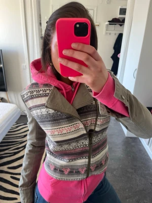 Grön jeansjacka  - Unik bikerjacka från F.A.M i grått med färgglada mönster i rosa, vitt och svart. Jackan har lång ärm, sned dragkedja och croppad passform. Materialet är en mix av bomull och polyester, perfekt för dig som vill sticka ut.