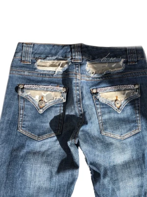 Lågmidjade bootcut jeans  - Lågmidjade bootcut jeans med camouflage  mönster på bakfickorna med lite strass 💫