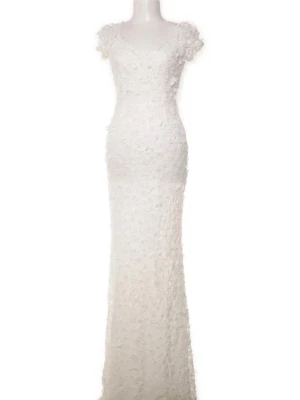 Ida Sjöstedt gigi dress - Elegant långklänning i vit spets med blommiga detaljer och korta ärmar. Klänningen har en figurnära passform och v-ringad halsringning. Perfekt för speciella tillfällen där du vill känna dig extra fin.