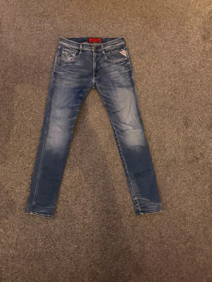 Blå slim fit jeans från Replay - Snygga blå slim fit jeans från Replay med  klassisk femficksdesign. Jeansen har en tvättad look med ljusare partier på låren och knäna . Perfekta för en trendig vardagsstil.