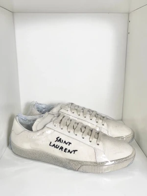 Vita Saint Laurent sneakers SL06 - Stilrena och eftertraktade sneakers från Saint Laurent, perfekta sommarskon! Nyskick, inga defekter. Endast skor. Storlek 42,5 passar även 43. Kontakta mig för fler frågor och funderingar!