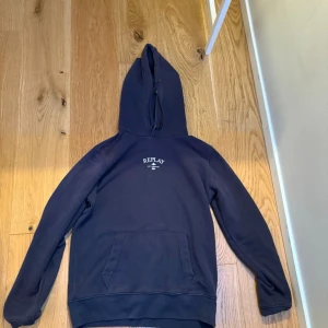 Mörkblå hoodie från Replay - Snygg mörkblå hoodie från Replay med klassisk huva och magficka. Diskret logga på bröstet och raka ärmar. Perfekt för en avslappnad och cool stil. Tillverkad i mjukt bomullsmaterial som känns skönt mot huden.