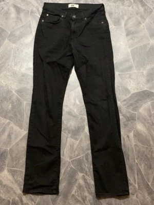 Svarta slim fit raka jeans från 304 - Snygga svarta jeans från 304 med klassisk femficksmodell och raka ben. Jeansen har normal midja, knappgylf och är tillverkade i ett mjukt denimtyg som ger en skön passform. Perfekta för dig som gillar en clean och enkel stil.