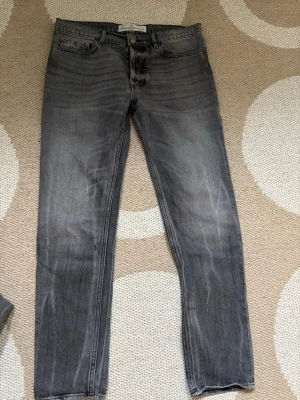 Grå jeans från Golden Goose - Säljer ett par grå jeans från Golden Goose Deluxe Brand med klassisk femficksmodell och raka ben. Jeansen har en snygg tvättad look och är tillverkade i denim. Perfekta för dig som gillar en avslappnad men stilren stil. Storlek 29