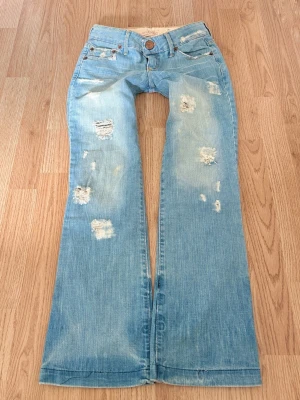 Ljusblå vintage slitna bootcut jeans - Sååå sjukt snygga vintage ljusblå bootcut jeans med slitna detaljer och hål! 