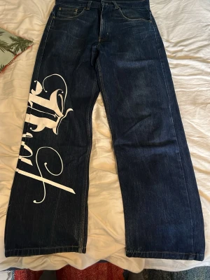 Baggy Jeans - Svin nice jeans baggy jeans med snyggt tryck på höger ben. Snygg passform och bra kvalitet. Perfekt för en skön 90s look!! De är faktiskt ruggigt snygga!!! Skriv för mer bilder och priset kan diskuteras. 