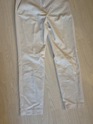 Vit/beiga Slacks strl 44 - Snygga vit/beigs slacks med rak passform och pressveck. Från H&M strl 44. Katt finns I hemmet