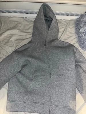 Grå zip-hoodie från H&M Loose - Säljer en grå zip-hoodie från H&M i modellen Loose. Hoodien har dragkedja framtill, stor huva och två fickor. Perfekt för en chill och avslappnad stil. Materialet är mjukt och skönt, passar bra till jeans eller joggers. Ny pris 500kr