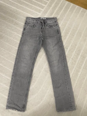 Grå raka jeans från 157 - Snygga grå jeans från 157 med rak passform och klassisk femficksdesign. Jeansen har bälteshällor och dragkedjegylf. Perfekta för en avslappnad och trendig look.