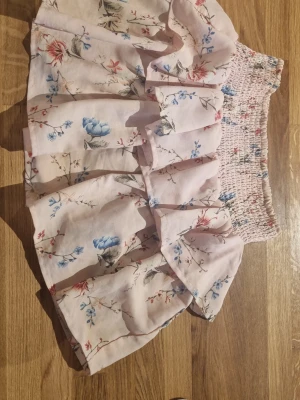 Ljusrosa blommig volangkjol - Supersöt ljusrosa kjol med blommigt mönster. En mini kjol