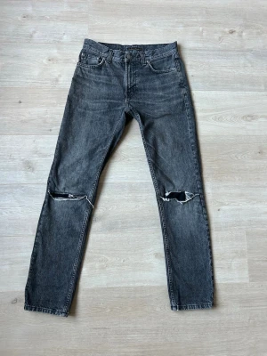 Gråa Nudie Gritty Jackson Jeans W29 L32 - Fina Nudie Jeans i grå färg. Jeansen är i mycket bra skick och sparsamt använda. |  Äkta som allt annat jag säljer! ✅ |  Storlek: W29 L32 | Skick: Mycket Bra Skick | Färg: Grå | Märke: Nudie | Modell: Jeans |   Hör gärna av dig vid frågor så svarar jag så fort jag kan! 😁 |  (SKU - 128)