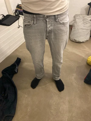 Ljusgrå raka jeans från Jack and Jones - Säljer ett par ljusgrå jeans med rak passform och klassisk femficksdesign. Jeansen har normal midja och är tillverkade i ett mjukt denimtyg. Perfekta för en avslappnad och stilren look.