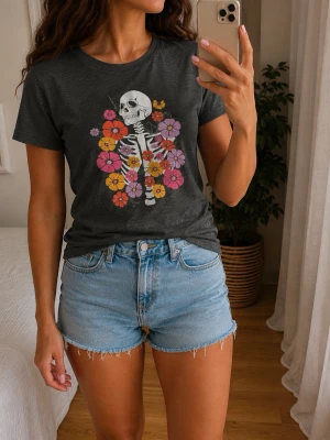 Svart t-shirt med skelett och blommor - Cool svart t-shirt med tryck av ett skelett omgivet av färgglada blommor i rosa, lila, orange och gult. T-shirten har rund hals och korta ärmar, perfekt för en avslappnad och trendig look.