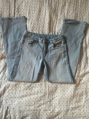 Ljusblå bootcut jeans - Säljer ett par ljusblå bootcut jeans med klassisk femficksdesign och normalhög midja. Jeansen har en avslappnad passform och är tillverkade i denim med lätt tvättad look. Perfekta för en casual och trendig stil. Har en liten grå fläck på knät. Storlek 152💗