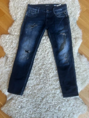 Mörkblå skinny jeans från Replay - Snygga mörkblå skinny jeans från Replay med slitningar och tvättade detaljer. Jeansen har fem fickor, låg midja och är tillverkade i stretchigt denim för en bekväm passform. Perfekta för en trendig och avslappnad stil.