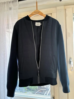 Mörkblå ziptröja från Opo Jeans - Snygg mörkblå ziptröja från Opo Jeans med quiltad framsida och stickade ärmar. Tröjan har ribbade muddar, två fickor och en diskret logotyp på ärmen. Perfekt för höst/sommar eller bara chill stil. Priset kan diskuteras vid snabb affär. 