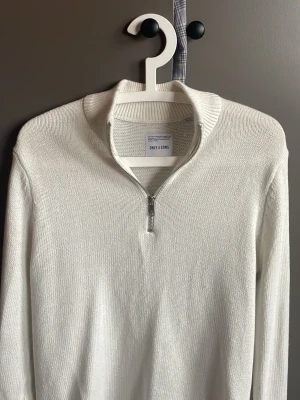 Vit stickad halvzip Only & Sons - Vit stickad tröja från Only & Sons med halvzip och hög krage i Nyskick. Tröjan har ribbade muddar vid ärmslut och nederkant, vilket ger en snygg och clean look. Perfekt för lager-på-lager och passar till jeans eller chinos.                         Hör gärna av er vid frågor eller funderingar!    Mvh Melker 