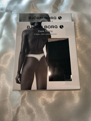 Björn Borg Core Thong 2-pack XS - Tvåpack stringtrosor från Björn Borg i modellen Core Thong. Trosorna är tillverkade i mjuk och stretchig bomull för en bekväm passform. Färgen är svart och designen är enkel och stilren med låg midja.