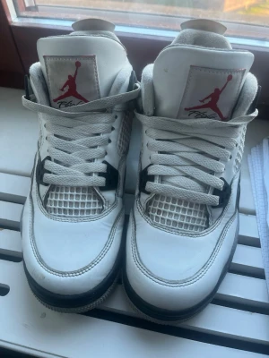 Air Jordan 4 Retro White Cement - Säljer ett par Air Jordan 4 Retro White Cement sneakers från Nike. Skorna är vita med grå och svarta detaljer, har snörning och meshpaneler på sidorna. Ikonisk Jumpman-logga på tungan och Nike Air på hälen. Perfekt för dig som vill ha klassiska och stilrena sneakers. Köpta på JD för nått år sen och är i storlek 37,5. Jag har tyvärr inte skolådan kvar. Pris går att diskutera.