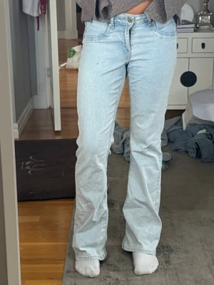 Lågmidjade  jeans - Säljer ett par lågmidjade ljusblå bootcut/straight jeans. Jeansen har en avslappnad passform och är tillverkade i denim. Dom är stretchiga så skulle säga att dem passar både M och L. Står inte vilket märke dom är ifrån. Innerbenslängden är 77-78cm och midjemåttet rakt över är 40-41 cm. Dom är i bra skick och pris kan diskuteras!