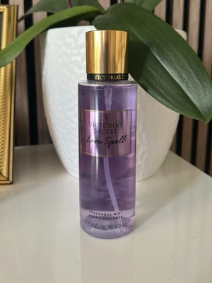 Victoria's Secret Love Spell parfym - Love Spell från Victoria's Secret är en parfymmist med en lila transparent flaska och guldfärgat lock. Flaskan rymmer 250 ml och har en elegant design med svart och guld detaljer. Perfekt för dig som gillar fruktiga och blommiga dofter.