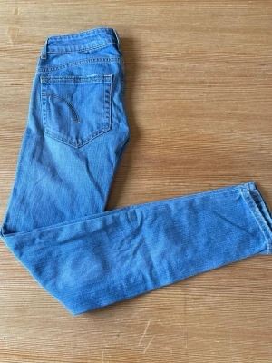 Blå jeans från Nudie Jeans - Säljer ett par klassiska blå jeans från dondup med raka ben. Jeansen har ljusblå tvätt och snygga detaljer på bakfickorna. Tillverkade i bomull och perfekta för en avslappnad stil.