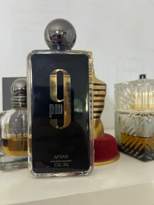 Afnan 9PM Edp 93ml  - Afnan 9PM är en elegant parfym i en rektangulär glasflaska med svart och guld etikett. Flaskan har en modern design med rundad silverfärgad kork och rymmer 100 ml. Doften är intensiv och passar dig som gillar stilrena och lyxiga parfymer. Köpte från afnan 93ml kvar 