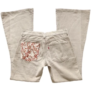 Vintage beiga lowwaist/ lowrise bootcut/ flare manchesterbyxor, Levi’s, blommor/ mönster/ hippie/ 60tal/ 70tal/ 2000tal - Supersnygga lågmidjade utsvängda manchesterbyxor från Levi’s! Med påsydd mönstrat tyg på ena fickan, 100% bomull 