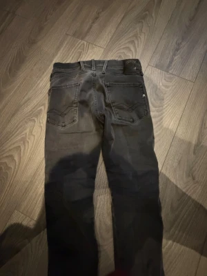 Svarta slim fit jeans från Replay - Snygga svarta slim fit jeans från Replay med klassiska fem fickor och diskreta sömdetaljer på bakfickorna. Jeansen har bälteshällor, knappgylf och Replay-logga på myntfickan. Tillverkade i stretchigt denim för skön passform.