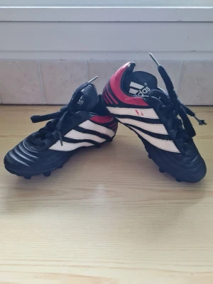 Adidas Predator 2001 Vintage fotbollsskor barn svart/vit/röd strl 29 - Adidas fotbollsskor för barn med dobbar och snörning. Svart/vit/röd modell predator 2001 vintage. Storlek 29.