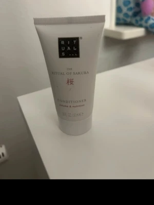 Rituals The Ritual of Sakura balsam - Volymgivande och närande balsam från Rituals, The Ritual of Sakura. Kommer i en vit tub med svart och rosa text, innehåller 50 ml. Perfekt för dig som vill boosta hårets volym och ge extra näring.