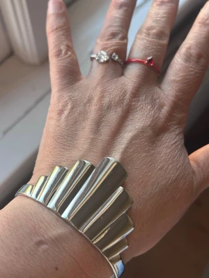 Edblad armband - Säljer ett coolt silvrigt armband med unik, vågig design som verkligen sticker ut. Armbandet är i metall och har en modern, geometrisk form med höga och låga partier. Perfekt för dig som gillar att addera en edgy touch till din stil.