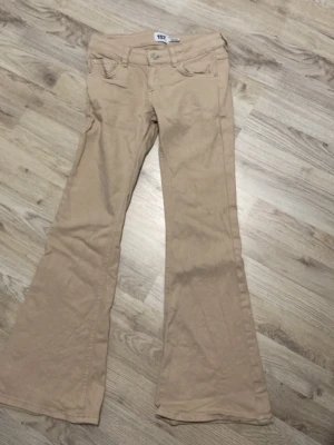 Beiga utsvängda jeans - Snygga beiga jeans med utsvängda ben, jeansen är från lager och är i bra skick, endast andvända 2 gånger! Jeansen är i modellen blaze star i strl 150.