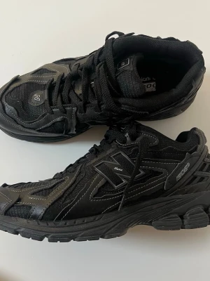 Svarta New Balance 2002R sneakers - Säljer ett par svarta New Balance 2002R sneakers med coola detaljer i syntet och mesh. Skorna har en chunky sula och reflekterande inslag, samt klassisk N-logga på sidan. Perfekta för dig som gillar streetwear och sportig stil.