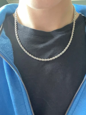 Cordell kedja 50-57cm 4mm - Säljer ett stilrent halsband i silverfärg med tvinnad kedja. Halsbandet har en klassisk design som passar till många olika stilar och stängs med ett karbinlås. Perfekt accessoar för att lyfta din outfit. Rostfritt stål, nytt endast testad köpt som gåva. Nypris 499kr. Kvitto finns på sista bilden