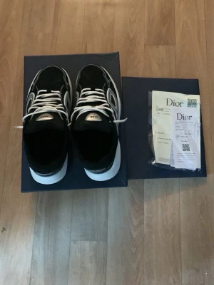 Svarta b30 - Snygga svarta sneakers med vita och grå detaljer samt vita skosnören. Skorna har en chunky sula i vitt och svart och en modern, sportig design. Märkeslogga på plösen och stilrena linjer längs sidorna. Perfekta för dig som vill ha något  och trendigt.