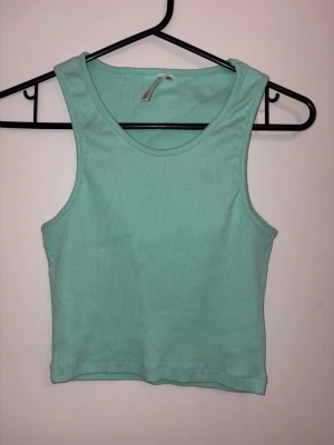 Mintgrön ribbad crop top från Lager157 - Snygg mintgrön ribbad crop top från Lager157 med breda axelband och rund halsringning. Tillverkad i mjukt stretchigt material som sitter skönt på kroppen. Perfekt att matcha med höga jeans eller kjol för en fräsch look. (M/L = barnstorlek)