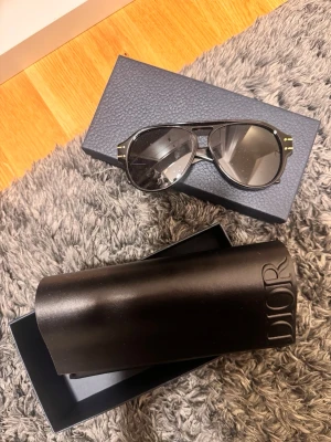 Svarta solglasögon från Dior - Snygga svarta solglasögon från Dior med klassisk pilotform och gulddetaljer på bågarna. Kommer med originalfodral och box. Perfekta för dig som vill ha en lyxig accessoar med statement-känsla.