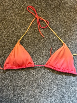 Färgglad triangelbikini med knyt - Snygg triangelbikini i ombre rosa och orange toner. Klassisk modell med knyt i nacken och ryggen, perfekt för stranden. Mjukt och stretchigt material som sitter bekvämt hela dagen.