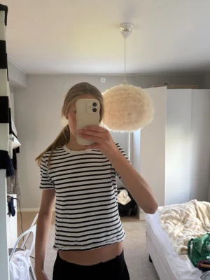 Randig t-shirt från Zara - Snygg kortärmad t-shirt från Zara i vitt med svarta horisontella ränder. Modellen är rak och lite croppad, perfekt till jeans eller shorts. Mjuk och skön bomullskänsla, klassisk rund halsringning. .